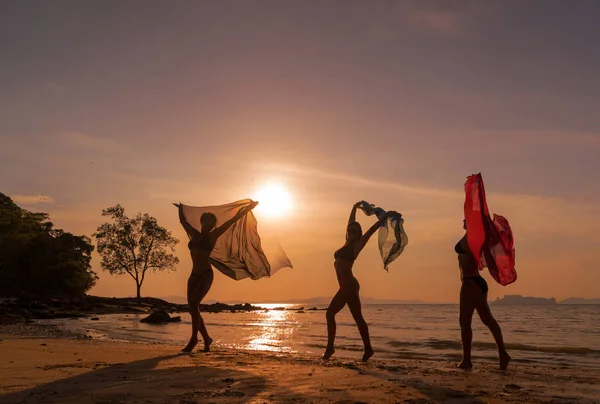 日落时分海滩上的三女孩剪影 — 图库照片