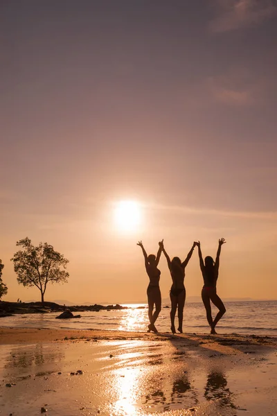 Silhouette di tre ragazze sulla spiaggia al tramonto — Foto Stock