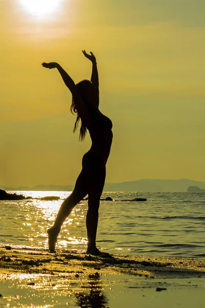 Silhouette d'une jeune femme en forme sur la plage au coucher du soleil — Photo