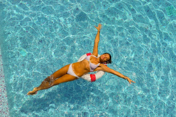 Mooie gebruinde vrouw in blauwe badmode ontspannen in zwembad spa. — Stockfoto