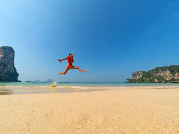穿着比基尼的无忧无虑的女人在沙滩上跳着双臂 outstret — 图库照片