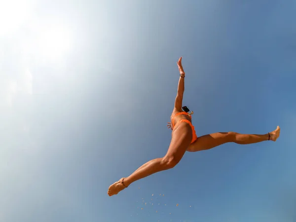 Unbekümmerte Frau im Bikini springt mit ausgestreckten Armen am Strand — Stockfoto