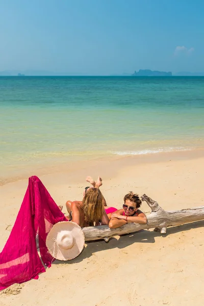 Due donne sedute sulla spiaggia vicino ad un albero — Foto Stock