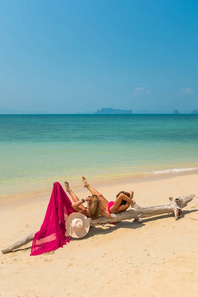 Due donne sedute sulla spiaggia vicino ad un albero — Foto Stock