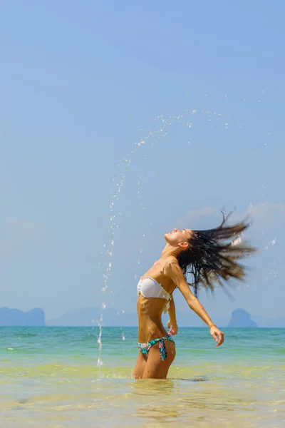 Bella ragazza spruzzi d'acqua con i capelli nel mare . — Foto Stock
