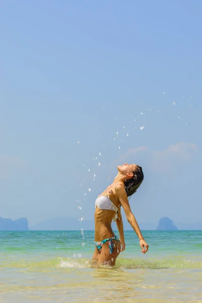 Schöne Mädchen, das Wasser mit ihren Haaren im Meer planscht. — Stockfoto