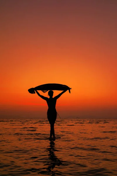 Silhouette egy fiatal és fitt nő a strandon naplementekor — Stock Fotó