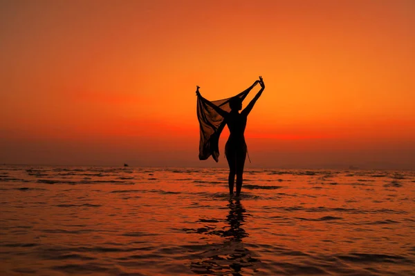 Silueta de una mujer joven y en forma en la playa al atardecer — Foto de Stock