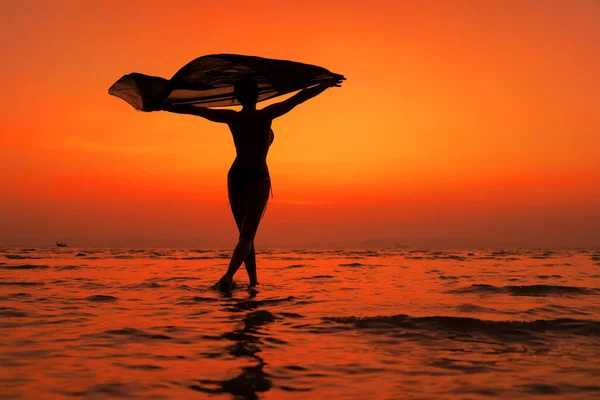 Silhouette egy fiatal és fitt nő a strandon naplementekor — Stock Fotó