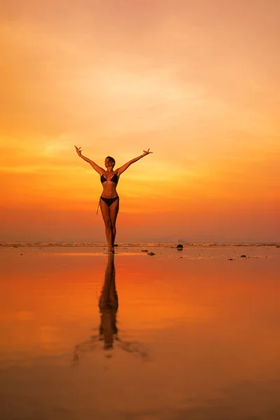 Silhouette egy fiatal és fitt nő a strandon naplementekor — Stock Fotó
