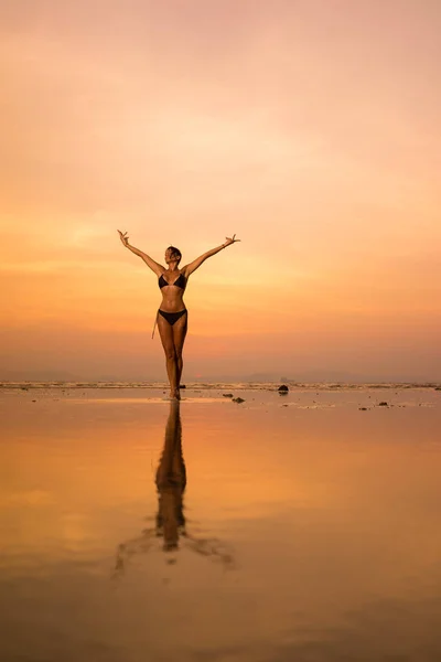 Silhouet van een jonge en fitte vrouw op het strand bij zonsondergang — Stockfoto