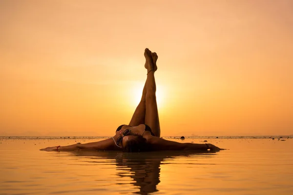 Silhouette d'une jeune femme en forme sur la plage au coucher du soleil — Photo