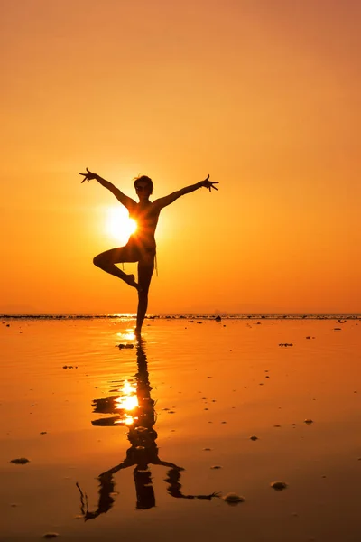 Silhouette of a young and fit woman on the beach at sunset — Stock Photo, Image