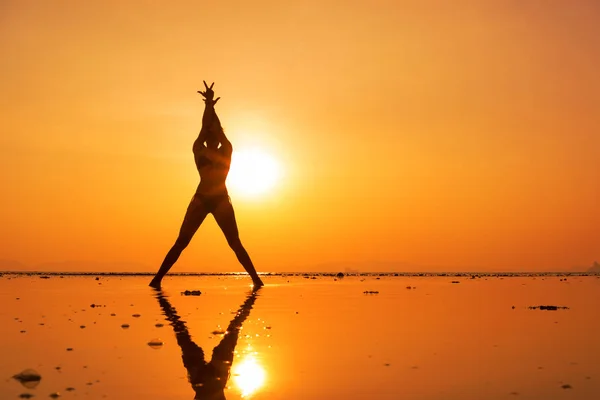 Silhouette d'une jeune femme en forme sur la plage au coucher du soleil — Photo