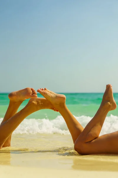 Dos hermosas piernas de las mujeres en la playa — Foto de Stock