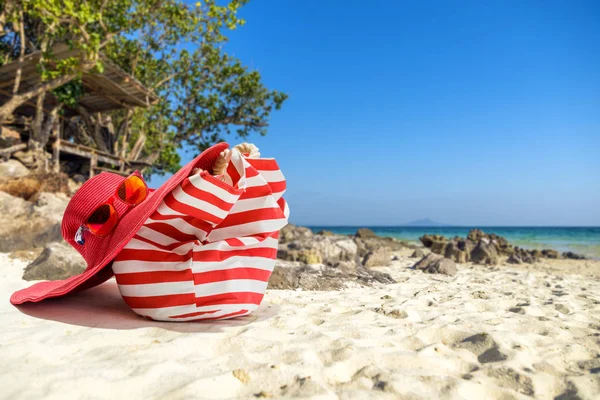 Chapeau de paille, sac, lunettes de soleil et tongs sur une plage tropicale — Photo