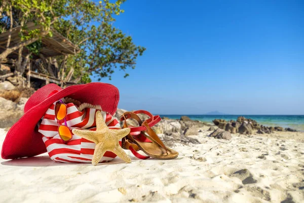 Chapeau de paille, sac, lunettes de soleil et tongs sur une plage tropicale — Photo