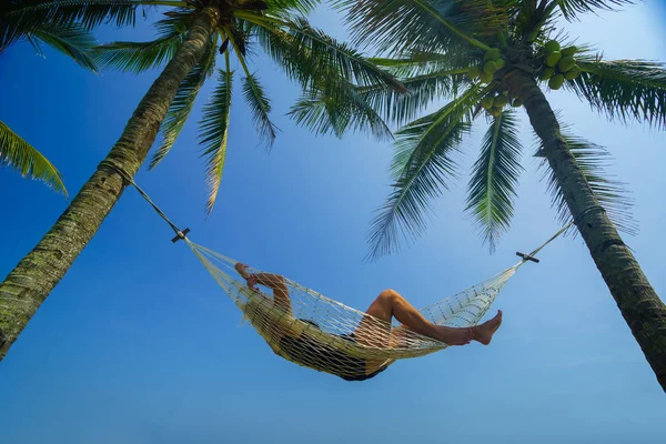 Женщина отдыхает на гамаке в тропическом пляжном курорте — стоковое фото