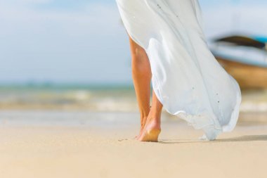 White pareo woman legs walking on tropical beach vacation. Close clipart
