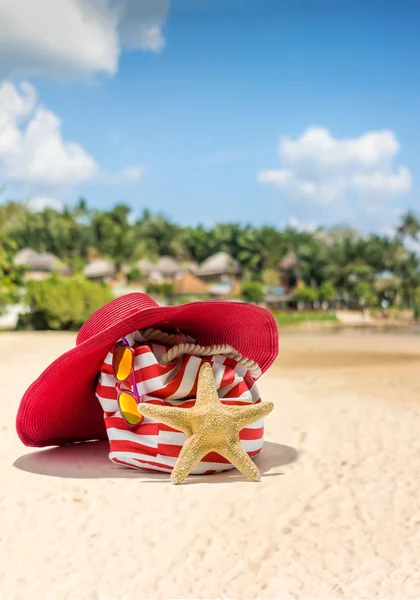Соломенная шляпа, сумка, солнцезащитные очки и шлепанцы на тропическом пляже — стоковое фото