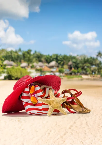 Chapéu de palha, bolsa, óculos de sol e chinelos em uma praia tropical — Fotografia de Stock