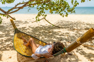 Kumsalda hamakta dinlenen bir kadın.