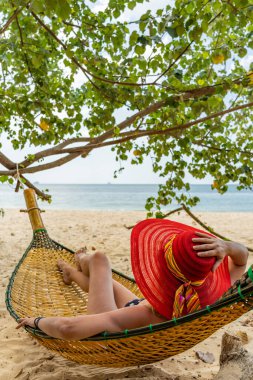 Kumsalda hamakta dinlenen bir kadın.