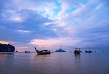 Geleneksel uzun kuyruklu tekne gün batımında Tayland sahilinde.