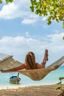 Kumsalda hamakta dinlenen bir kadın.