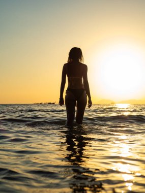 Gün batımında tropikal beyaz kumsalda genç bir kadın