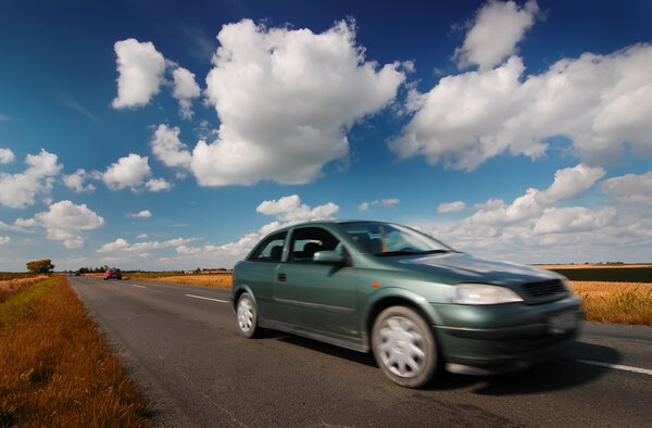 Car on road through countryside with beauty clouds