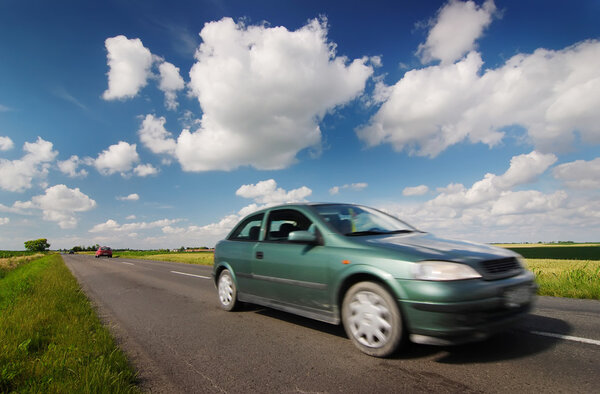 Car on road through countryside with beauty clouds