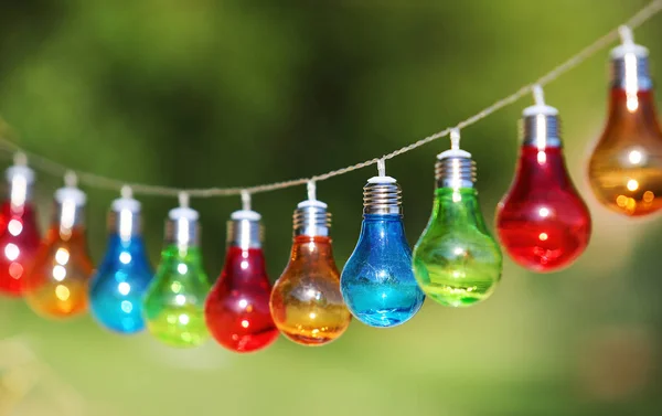 Kleurrijke lampen hangen tekenreeks buiten — Stockfoto