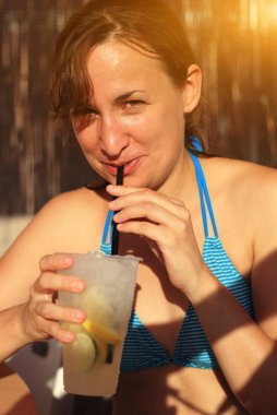 Yazın bikinili kokteyl içen genç bir kadın.