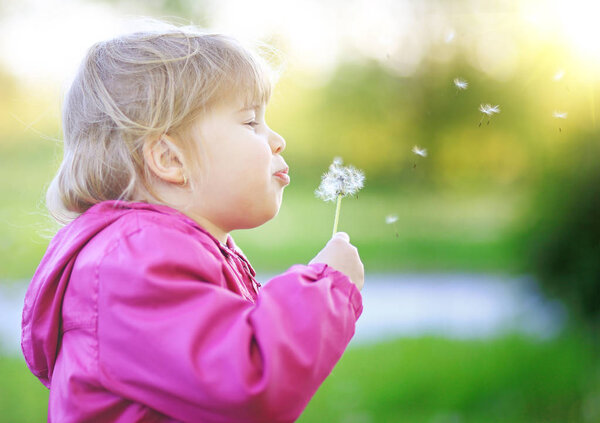 Cute child blow dandelion outdoor