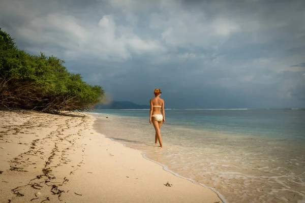 Jonge vrouw wandelen langs tropisch strand — Stockfoto