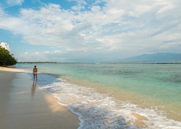 Young woman walking along tropical beach — Stock Photo, Image