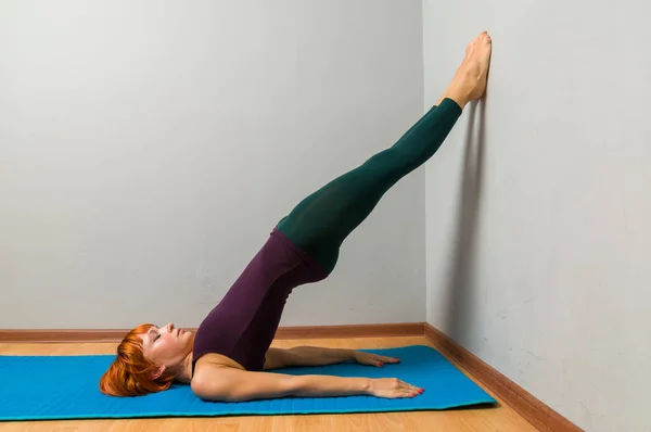 Yoga posando em um fundo de estúdio cinza — Fotografia de Stock