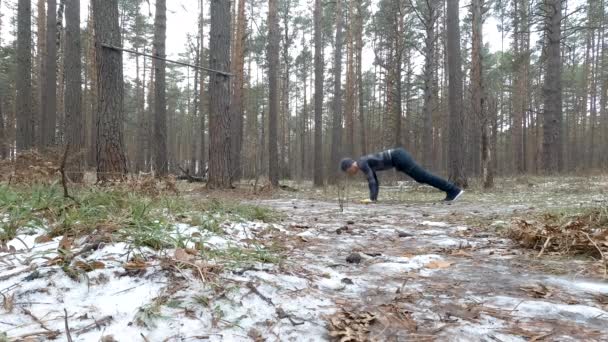 Joven atlético realiza flexiones en el bosque — Vídeo de stock