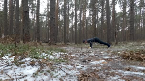 Joven atlético realiza flexiones en el bosque — Vídeo de stock
