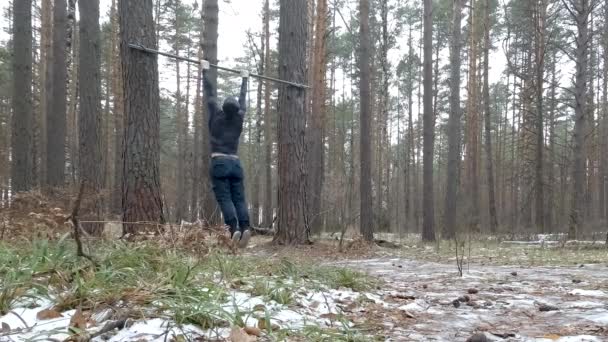 Hombre atlético joven realiza Pullups en el bosque — Vídeo de stock