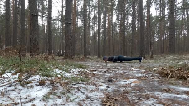 Молодой спортсмен отжимается в лесу — стоковое видео