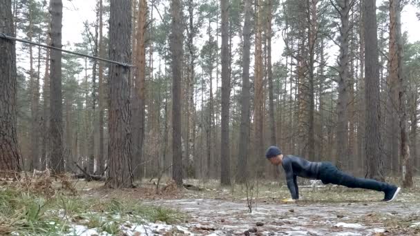 Jonge atletische man voert Pushups in het bos — Stockvideo