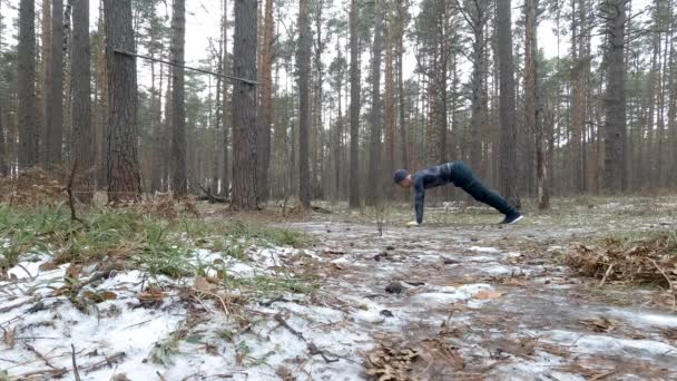 Молодой спортсмен отжимается в лесу — стоковое видео