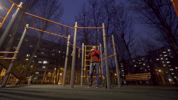 Hombre haciendo ejercicio en el campo de deportes por la noche — Vídeos de Stock