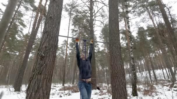 Hohe Klimmzüge. Sportlicher junger Mann trainiert im Wald — Stockvideo