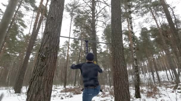 Jeune homme athlétique travaillant avec bande de résistance en caoutchouc dans la forêt — Video