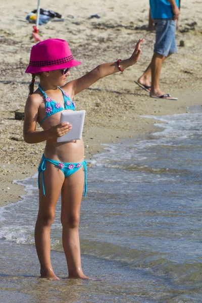 Niña con tableta en la playa durante las vacaciones de verano — Foto de Stock