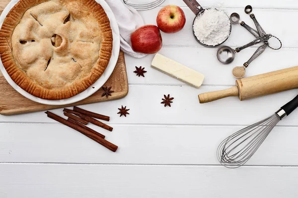 Apfelkuchen mit Zutaten über Holztischplatte — Stockfoto