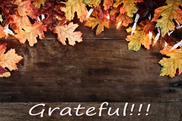 Őszi levelek fények és hálás szöveg fölött fából készült háttér — Stock Fotó